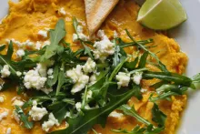 Hummus s kurkumou, kozím sýrem, rukolou a kapkou olivového oleje